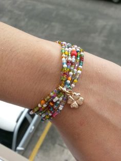 a woman's arm with bracelets on it and a car in the background