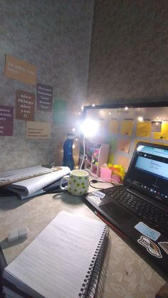 an open laptop computer sitting on top of a desk next to a note pad and pen