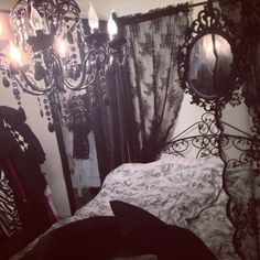 a bedroom with a bed, chandelier and mirror on the wall next to it