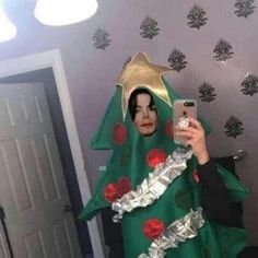 a woman in a green christmas tree costume taking a selfie