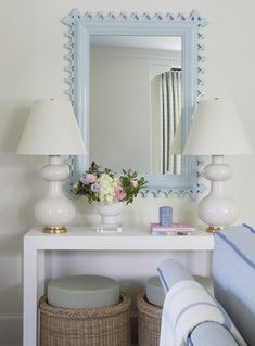 a white table topped with a mirror and two lamps next to a blue bench covered in flowers