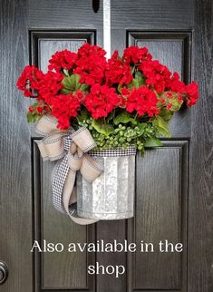 a metal bucket with red flowers hanging from it's front door and tied to the handle