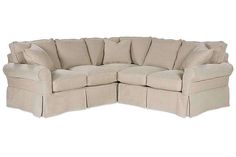 a large sectional couch with pleated pillows on the top and bottom corner, in beige