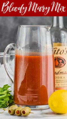 a pitcher filled with liquid next to some lemons