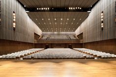 an empty auditorium with rows of chairs and lights hanging from the ceiling in front of it