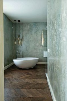 a bath tub sitting in the middle of a bathroom next to a wall mounted light