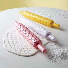 three different colored toothbrushes sitting on top of a white plate next to a yellow tube