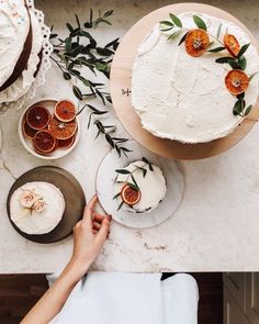 a table topped with cakes covered in frosting and orange slices on top of plates