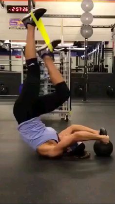 a man is doing an exercise with a medicine ball on his back in a gym