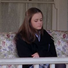 a woman sitting on top of a couch next to a window