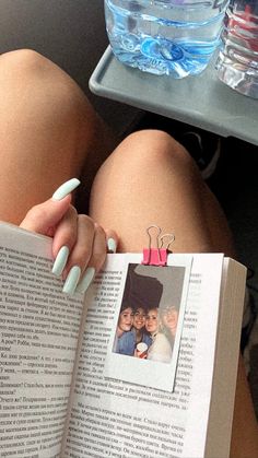 a woman laying on the floor reading a book with her legs crossed and nails painted green