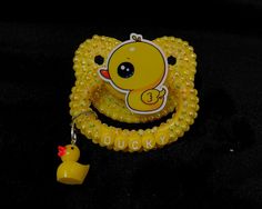 a rubber ducky pacifier with yellow beads and a rubber duck charm on it