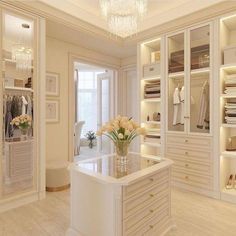 a large white closet filled with lots of clothes and flowers on top of a counter