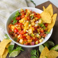 a white bowl filled with salsa and tortilla chips on top of a wooden cutting board