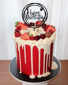 a red and white birthday cake with strawberries on top