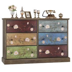 an old dresser with flowers painted on the drawers and candles in vases next to it