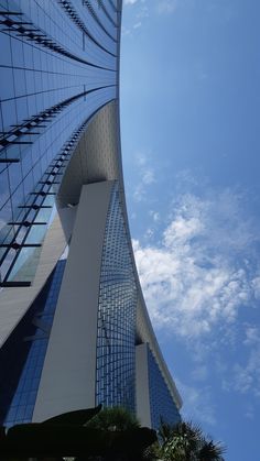 the curved building has many windows on it's sides and is next to palm trees