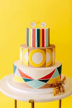 a multi - tiered cake sitting on top of a table next to a yellow wall