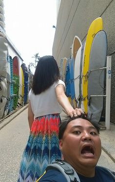 a man standing next to a woman with surfboards on the back of his head