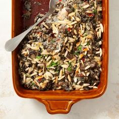 a bowl filled with rice and vegetables on top of a table next to a spoon