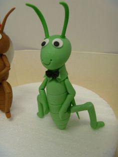 two toy bugs sitting on top of a white cake