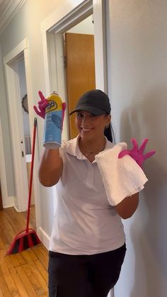 a woman in white shirt and black pants with pink gloves holding up two cleaning products