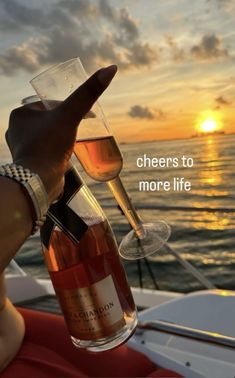 two people toasting wine glasses on a boat at sunset with the words cheers to more life