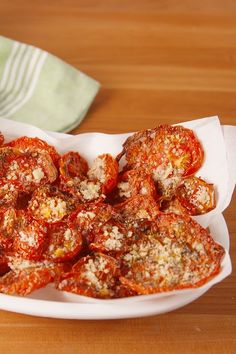 a white bowl filled with sliced tomatoes on top of a wooden table