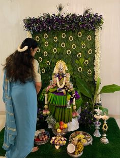 a woman standing in front of a display of flowers and other items on the ground