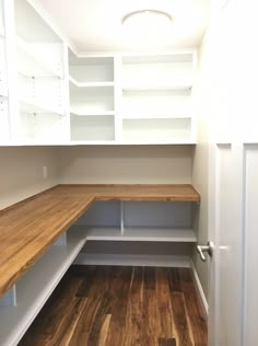 an empty room with white cabinets and wood flooring on one side, open shelves in the other