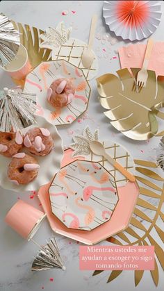 pink and gold party supplies on a white table with palm leaves, paper fans and plates