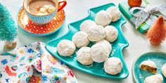 there are some snowball cookies on the table next to a cup of coffee and other decorations