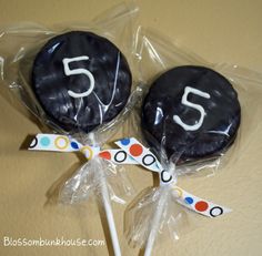 two black cake pops with the number five on them are wrapped in cellophane