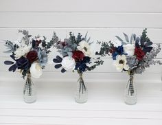 three vases filled with flowers sitting on top of a white table next to each other