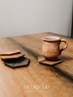 a wooden table with two coasters and a cup on it