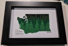 a cross stitch picture frame with the shape of indiana in green and black on it