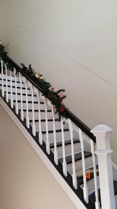 christmas garland on the bannister rail of a staircase with white handrails