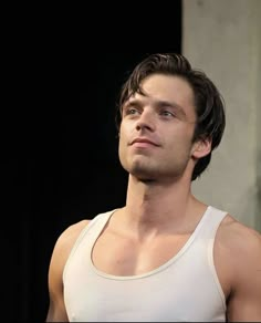 a young man in a tank top looking off into the distance