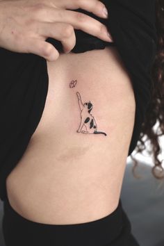 a woman's stomach with a small tattoo of a dog catching a frisbee