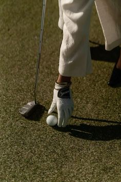 a close up of a person's foot wearing white shoes and holding a golf club