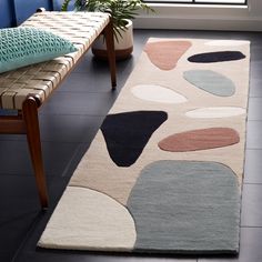 a rug with various shapes and colors on the floor in front of a blue wall