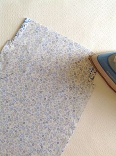 an iron on top of a piece of fabric next to a blue and white flowered cloth