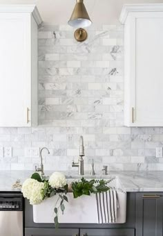 a kitchen with marble counter tops and white cabinets in the background is a sink that has flowers on it