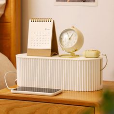 an alarm clock sitting on top of a table next to a calendar and phone holder