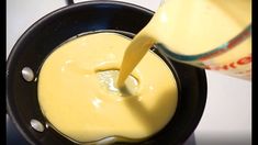 a person pouring yellow liquid into a frying pan