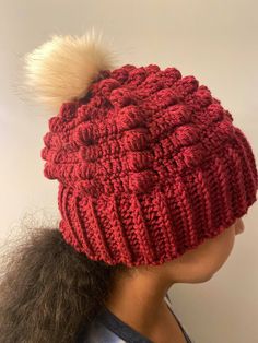 a woman wearing a red knitted hat with a white pom - pom