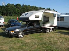 an rv is parked in the grass next to other cars and trucks with awnings