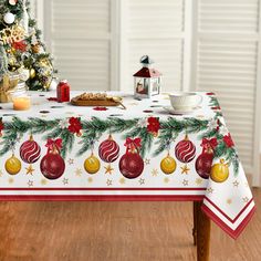 a christmas table cloth with ornaments and baubles on it, next to a small tree