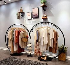 two circular racks with clothes hanging on them in front of a wall mounted display case