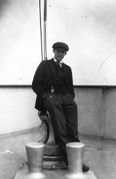 black and white photograph of a man sitting on a bench with buckets in front of him